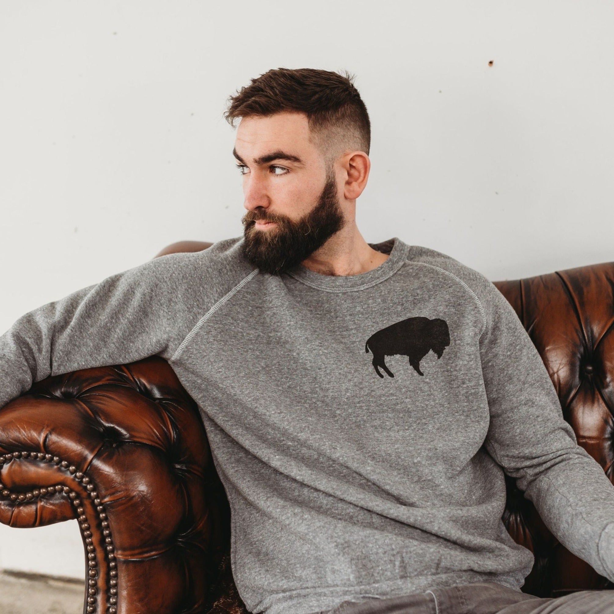 Bearded man wearing buffalo crewneck sweatshirt in grey