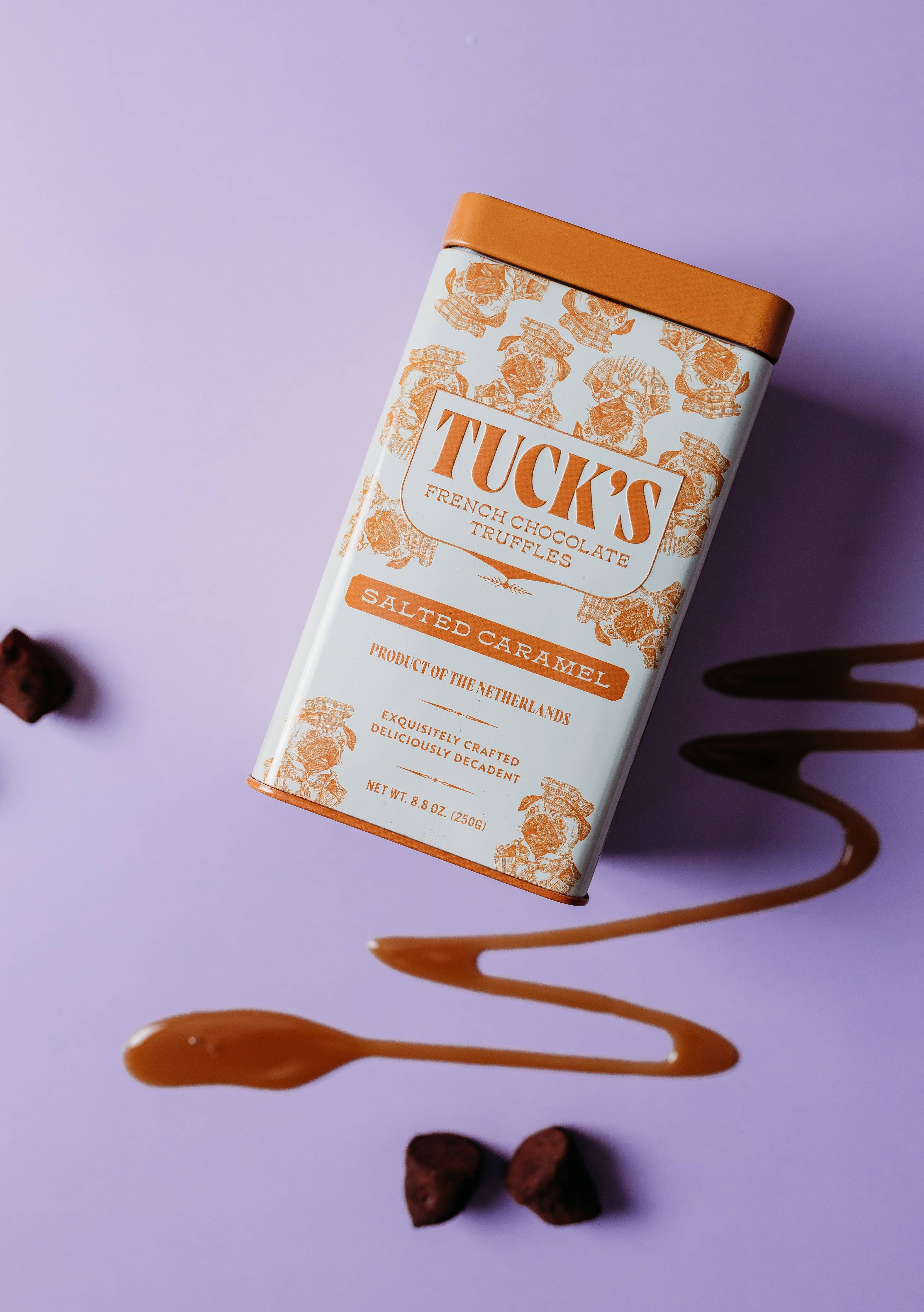 Tuck's salted caramel chocolate truffles packaging on a purple background with drizzled caramel and truffles.
