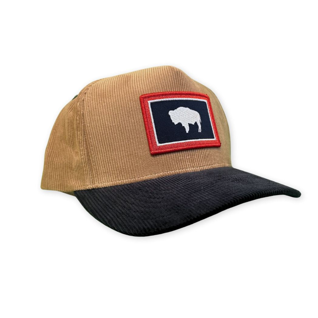 Tan and black cap with a patch featuring a buffalo on a white background