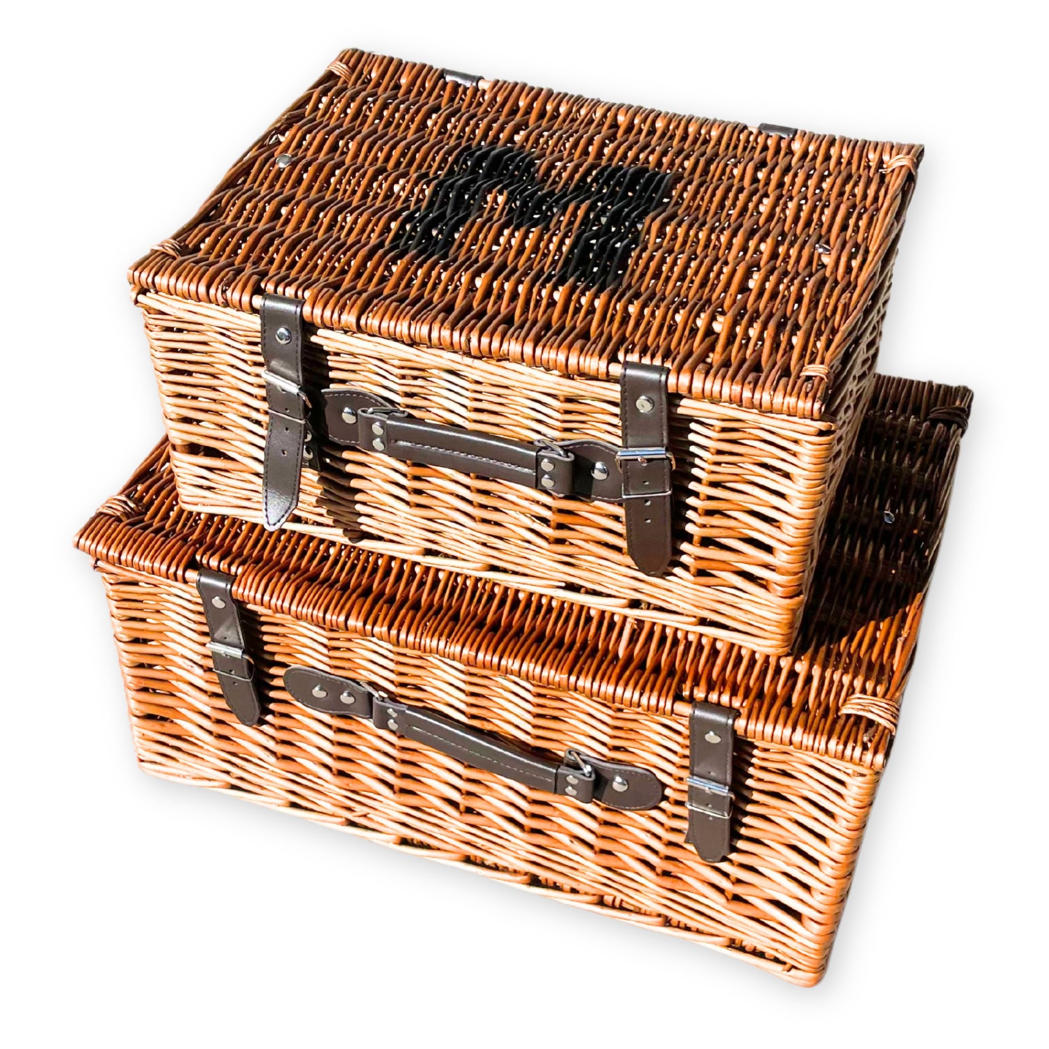 Two brown wicker hamper baskets with black handles and a letter 'M' logo on the lid of one basket.