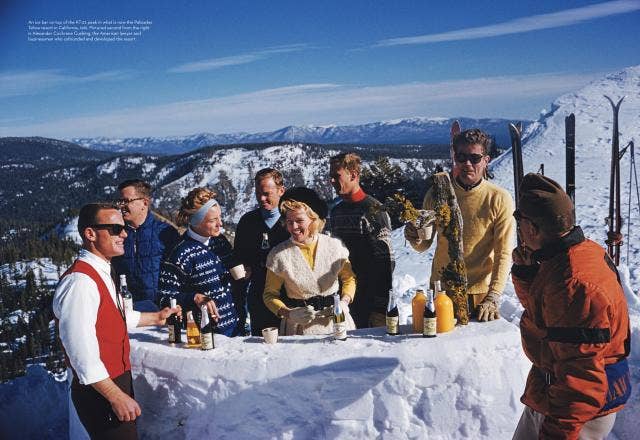 Group of people enjoying a meal in the snow with a scenic mountain view.