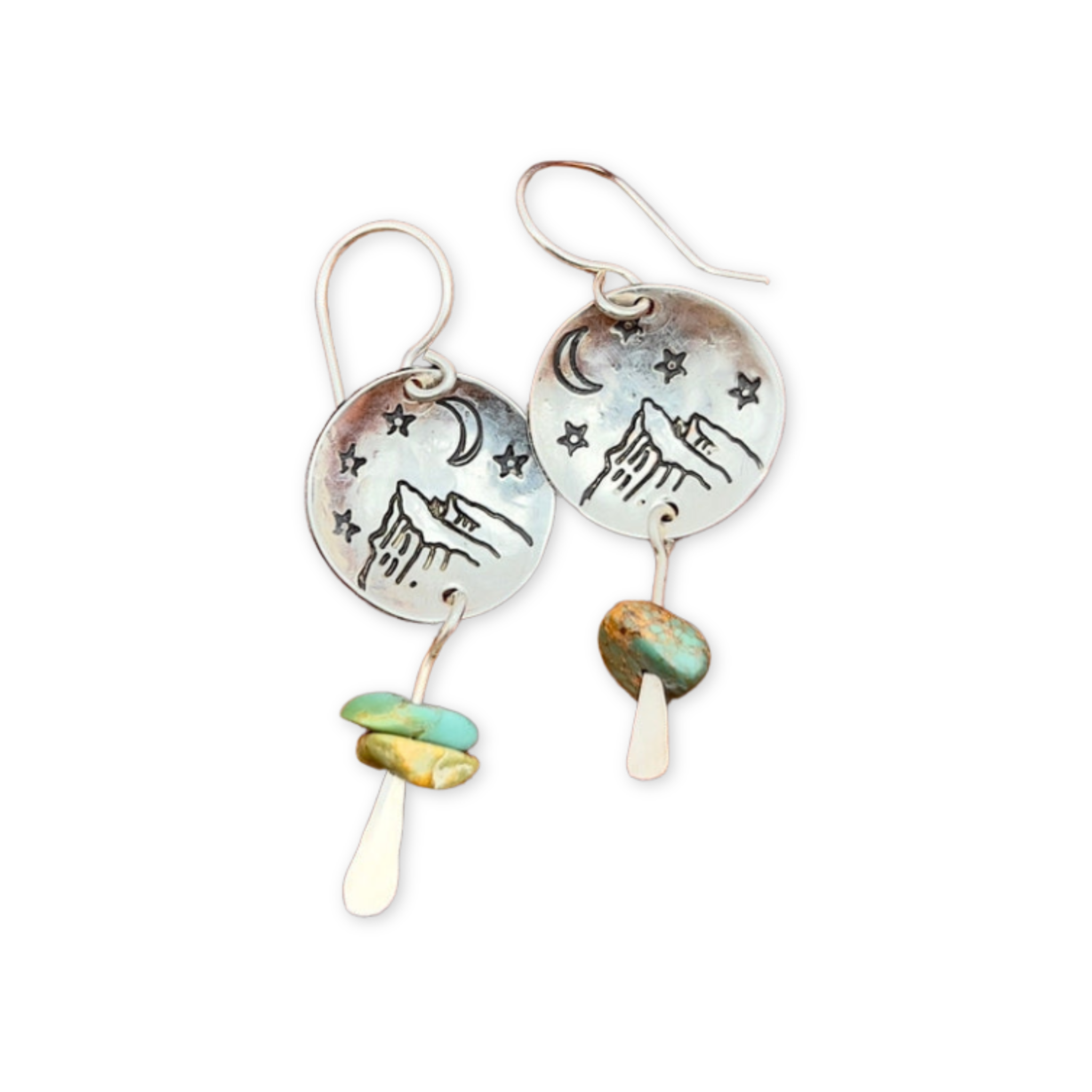 earrings featuring round disc pendants stamped with a mountain and night sky and hanging turquoise stones
