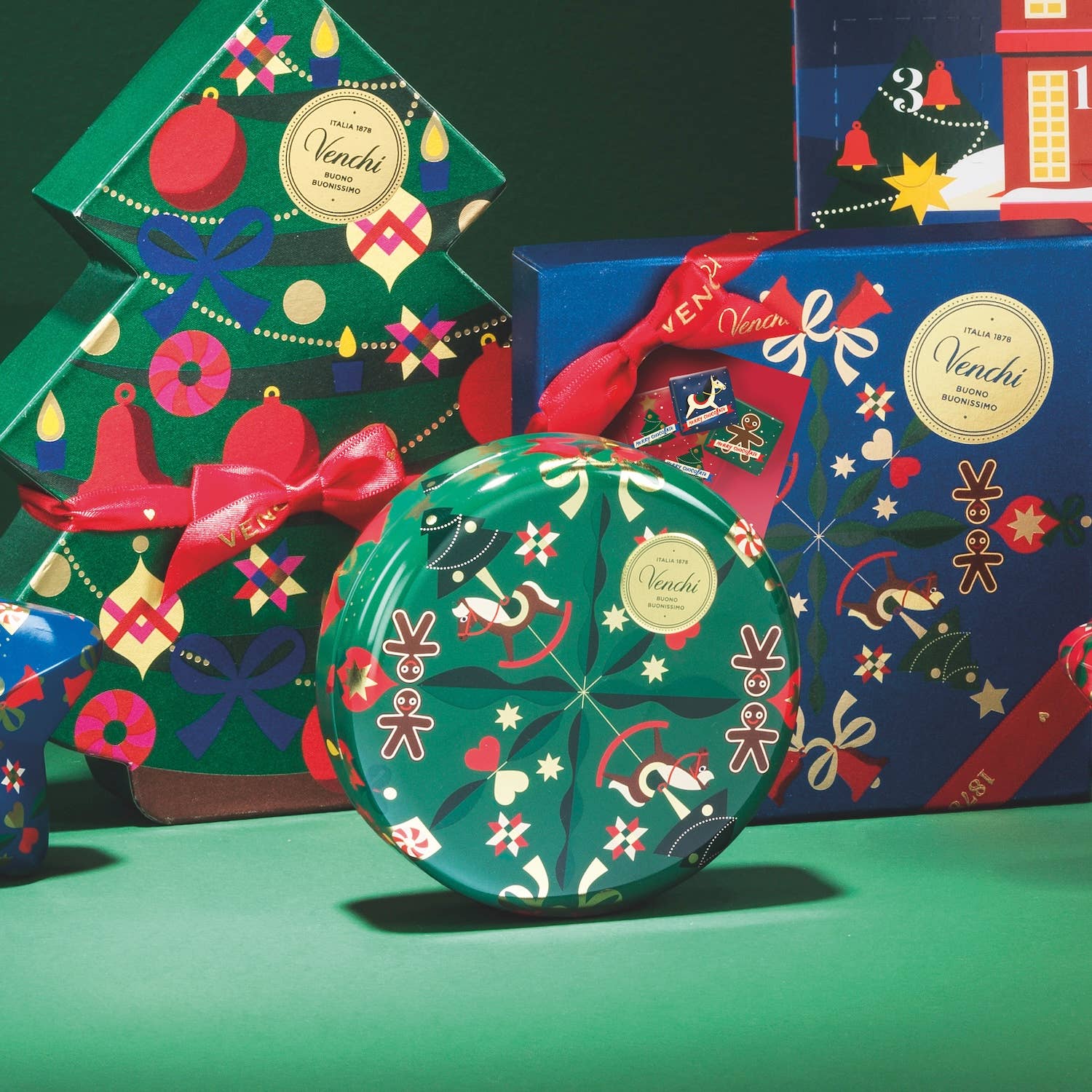 Decorative cookie tins with festive designs and 'Venchi' branding on a green background.