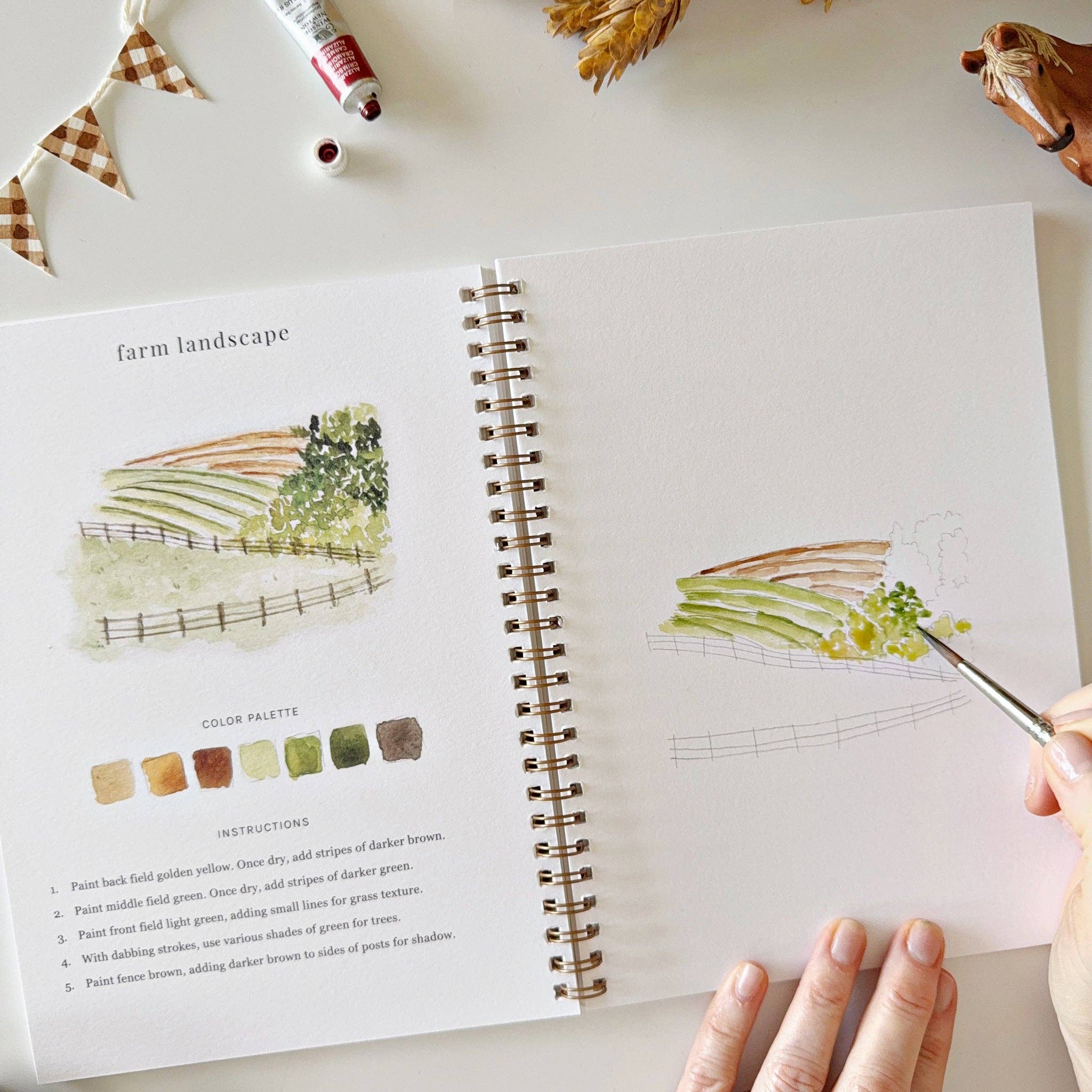 Open art book with illustrations and color palette on a table