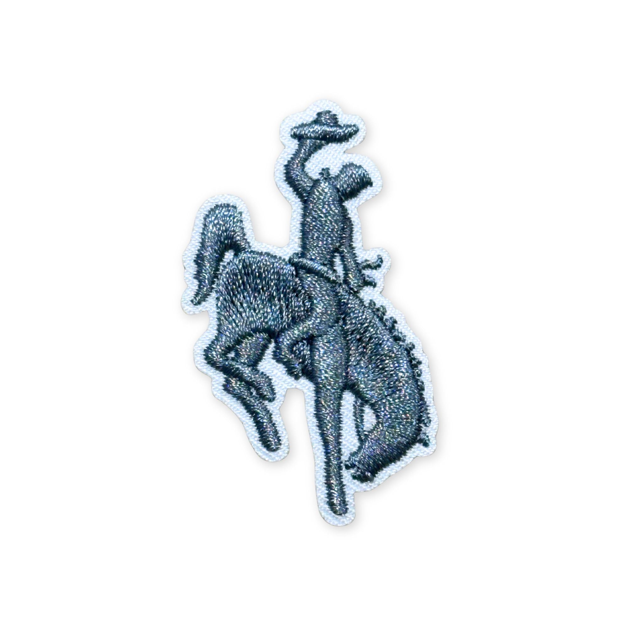 Embroidered patch, showing the silhouette of a bucking bronco and cowboy in grey stitching and white boarder.