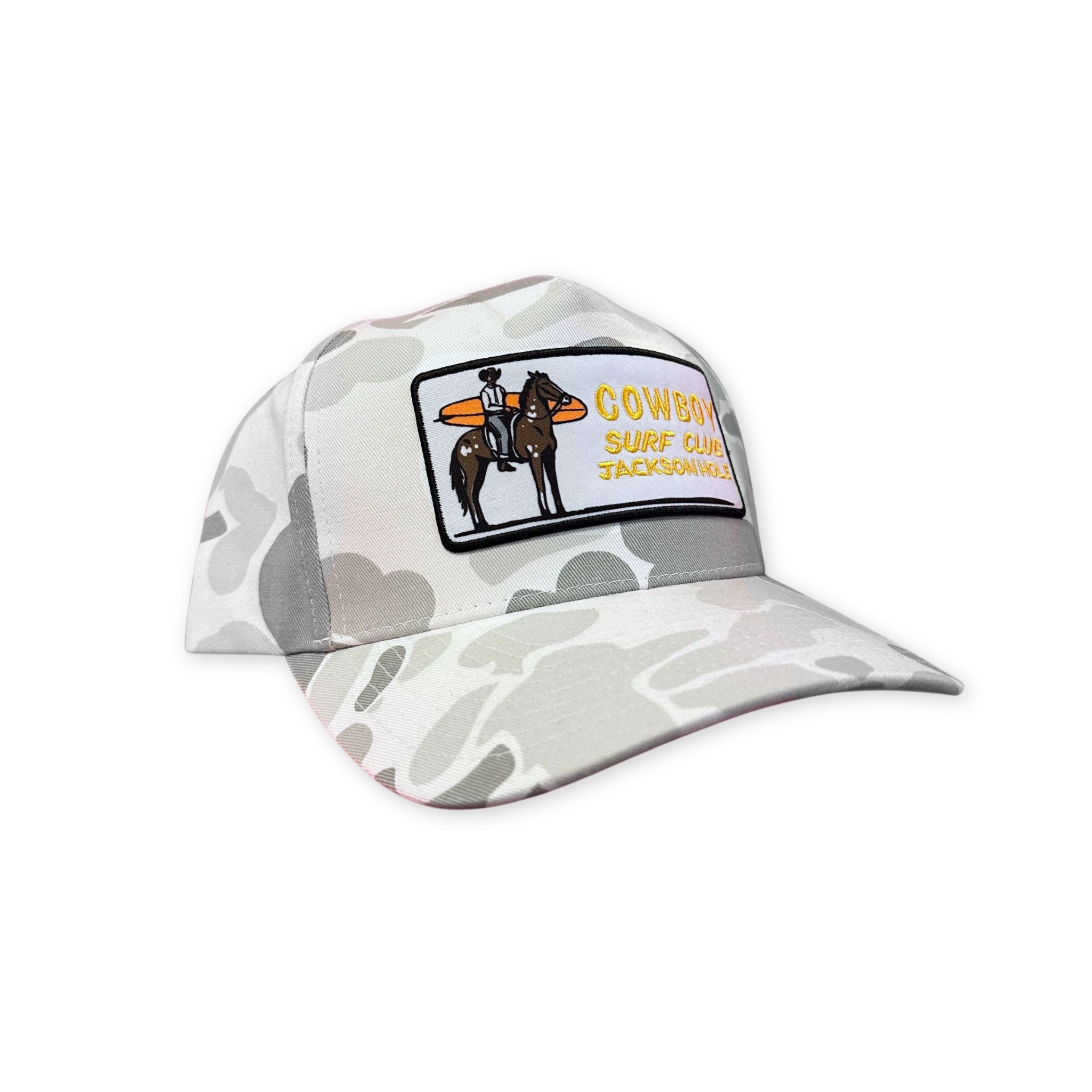 Grey and White camo trucker hat, with a cowboy holding a surfboard on a horse. In yellow text next to it "Cowboy Surf Club Jackson Hole"