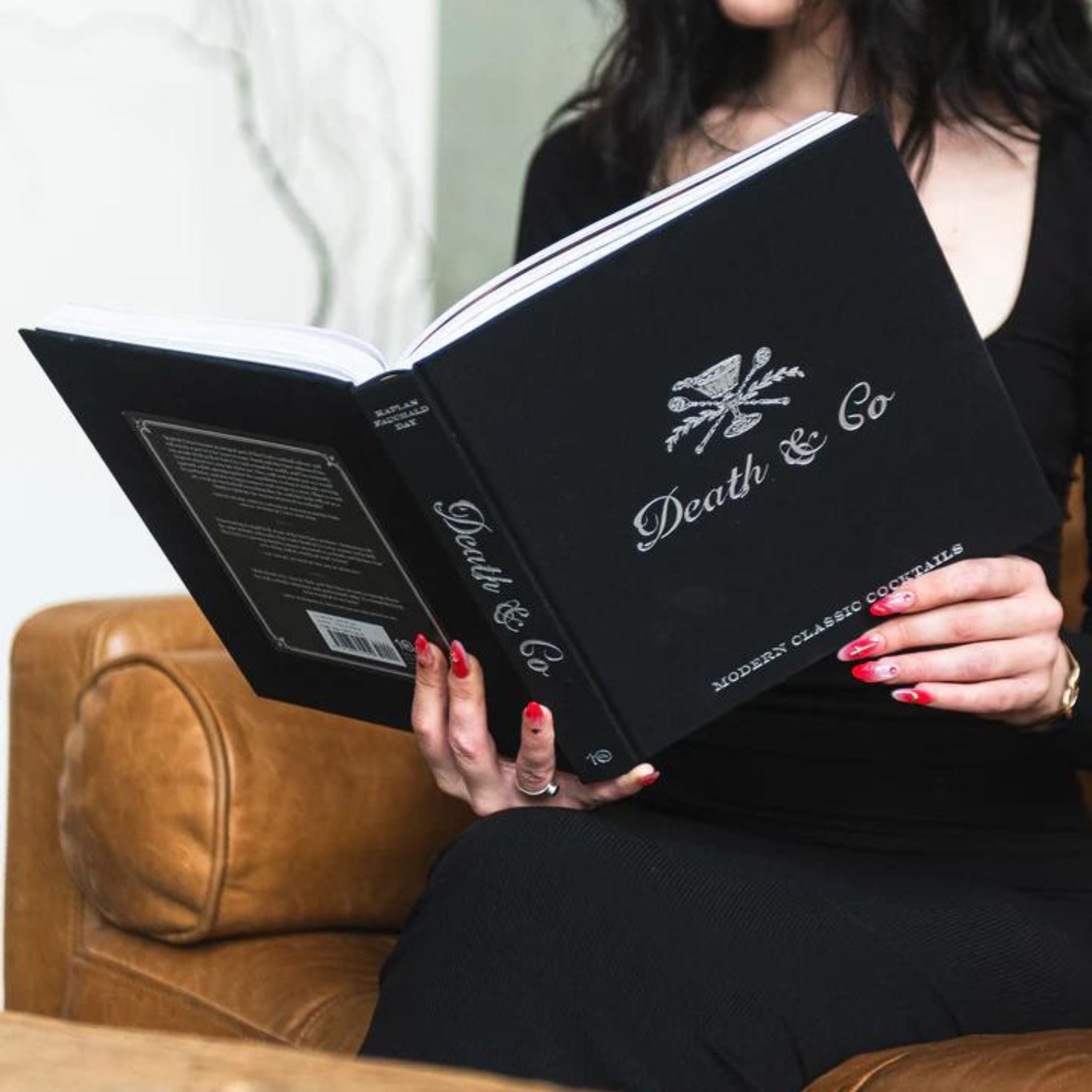 A woman reading the book by Death & Co.