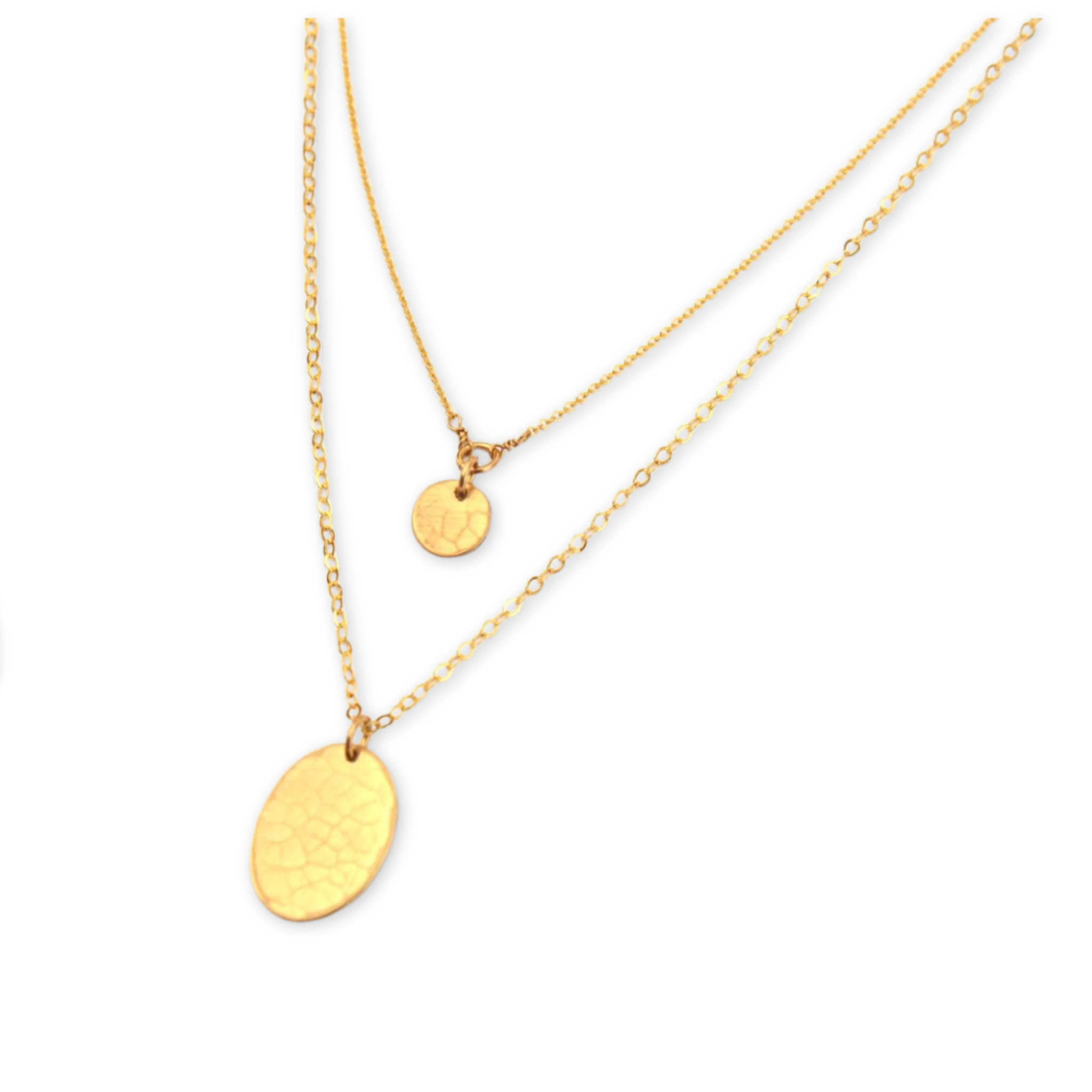 two layering necklaces featuring a textured round disc and a textured oval both hanging on simple chains 