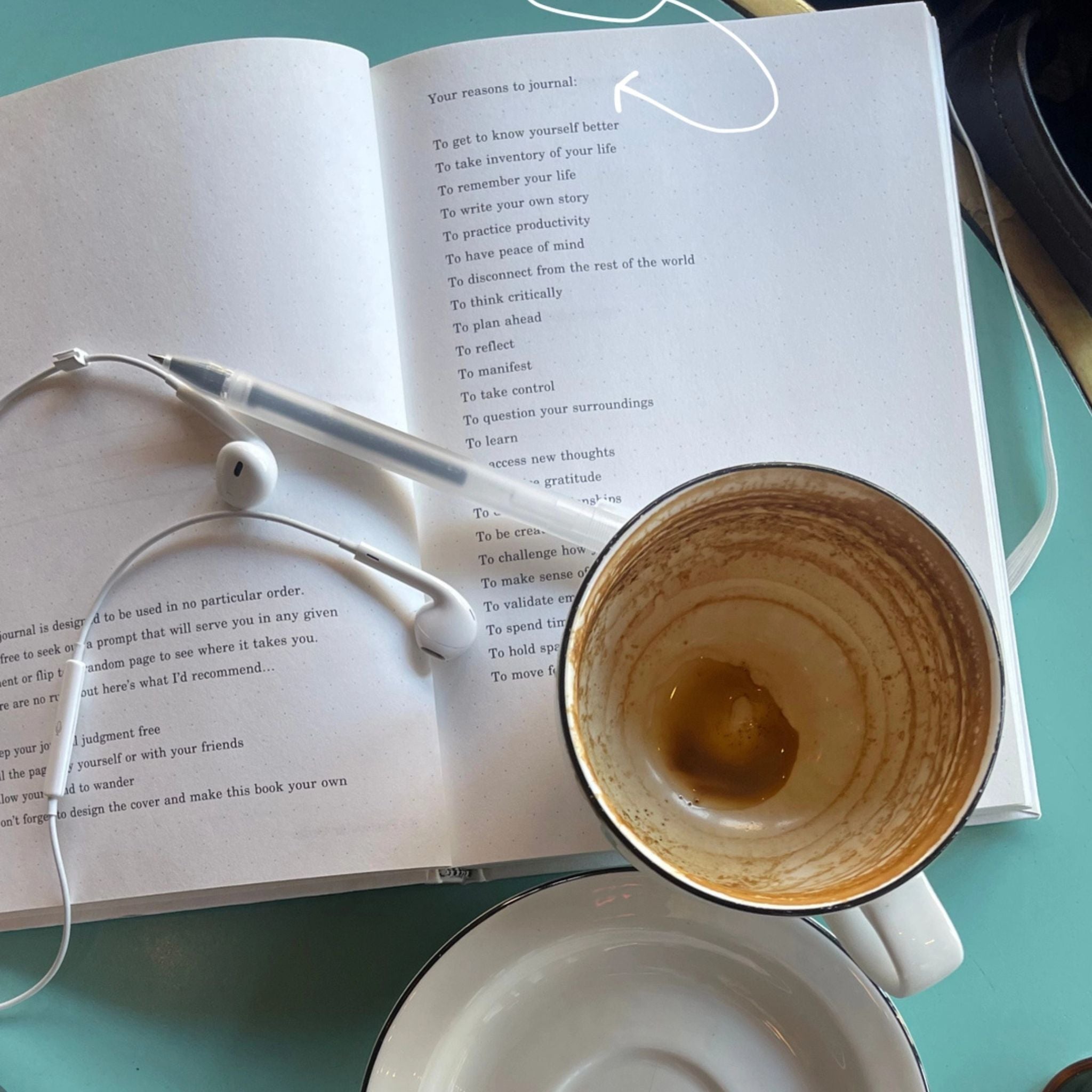 Open book with a cup of coffee and eyeglasses on a teal surface