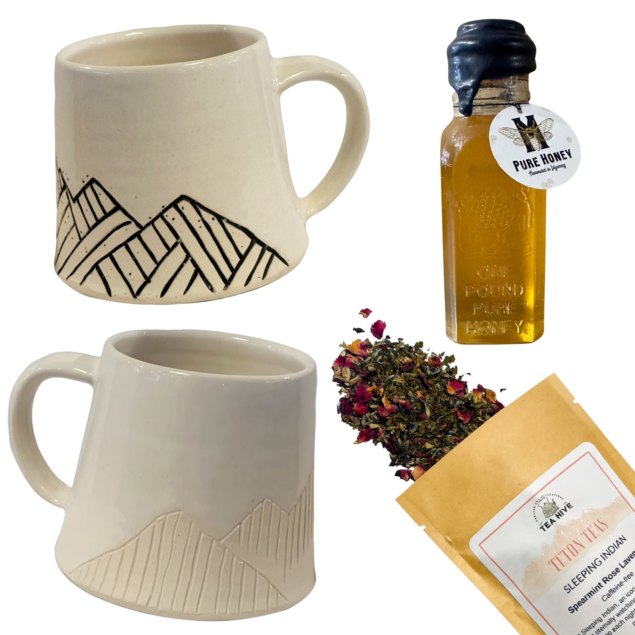 Two ceramic mugs with mountain designs, a bottle of honey, and a package of tea leaves on a white background.