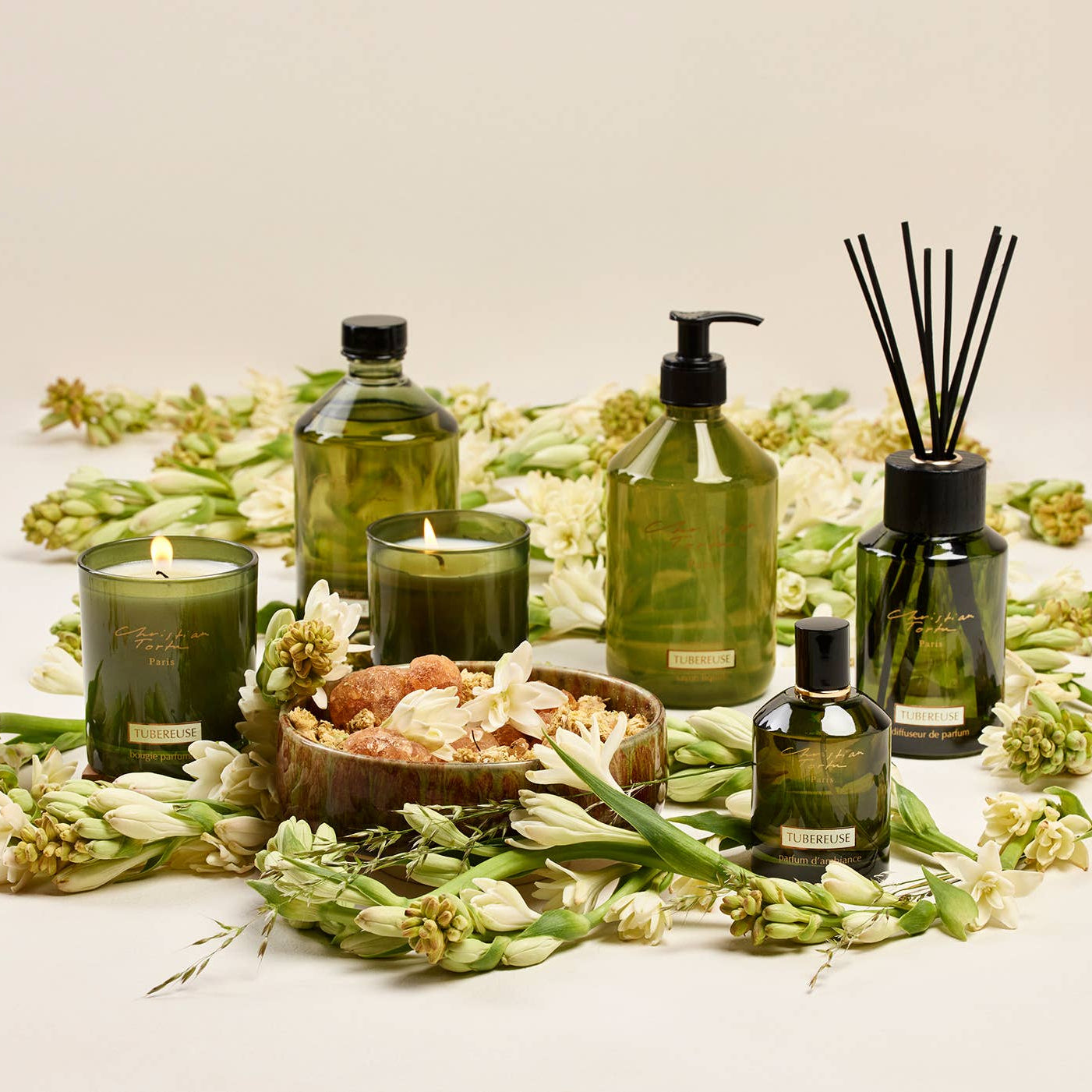 Green skincare products and candles with flowers on a light background