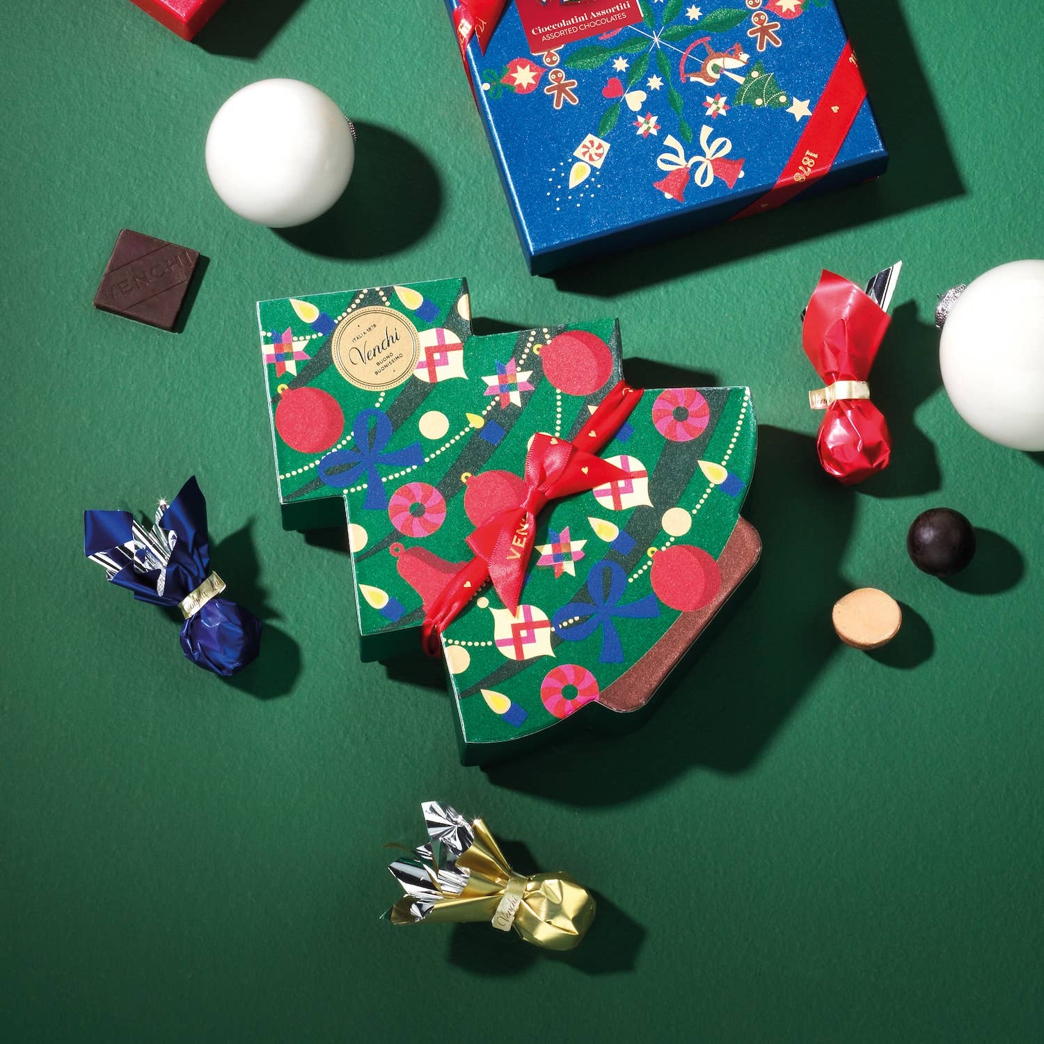 Colorful chocolate boxes with decorative ribbons on a green background