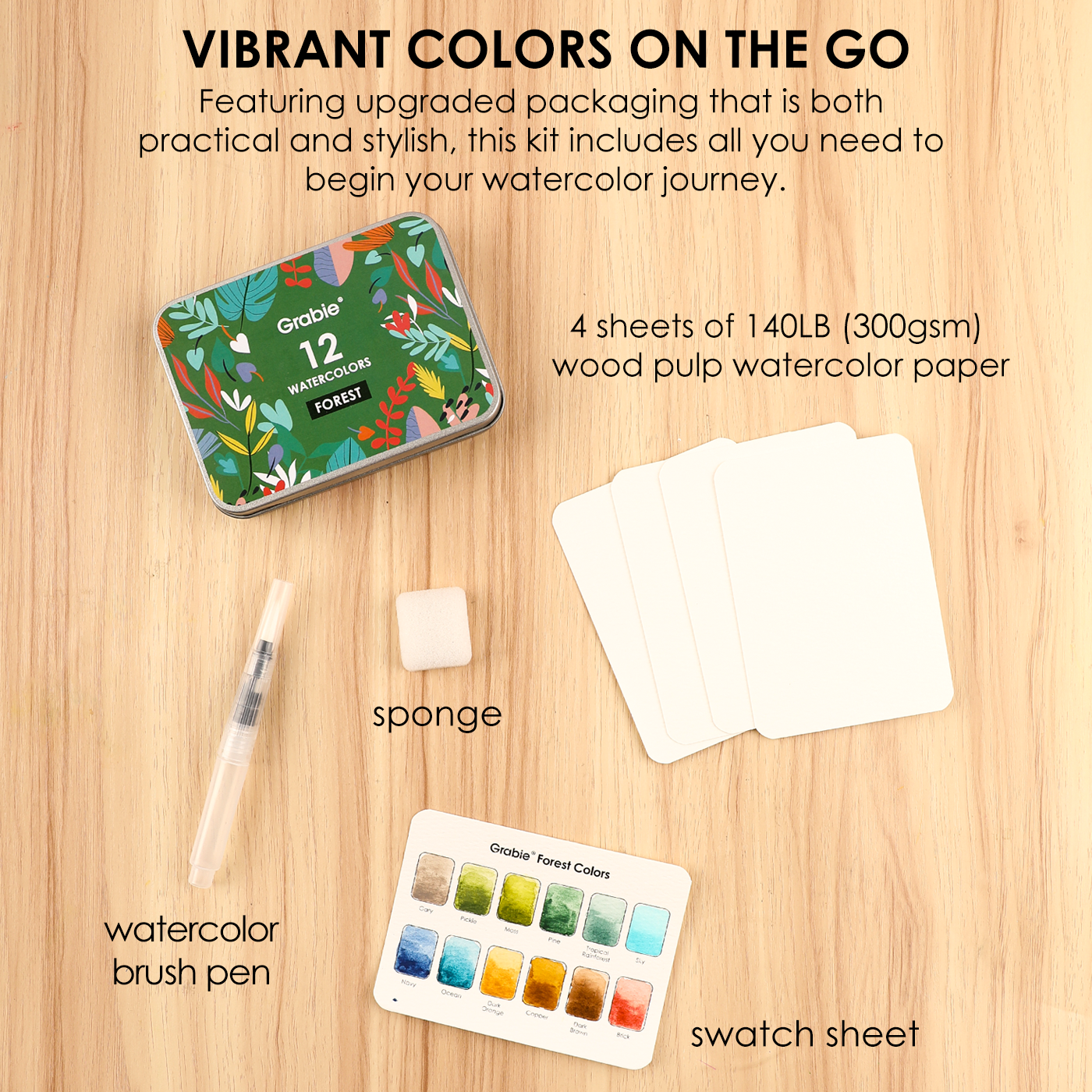 Watercolor kit with tin, paper, brush pen, sponge, and swatch sheet on a wooden surface