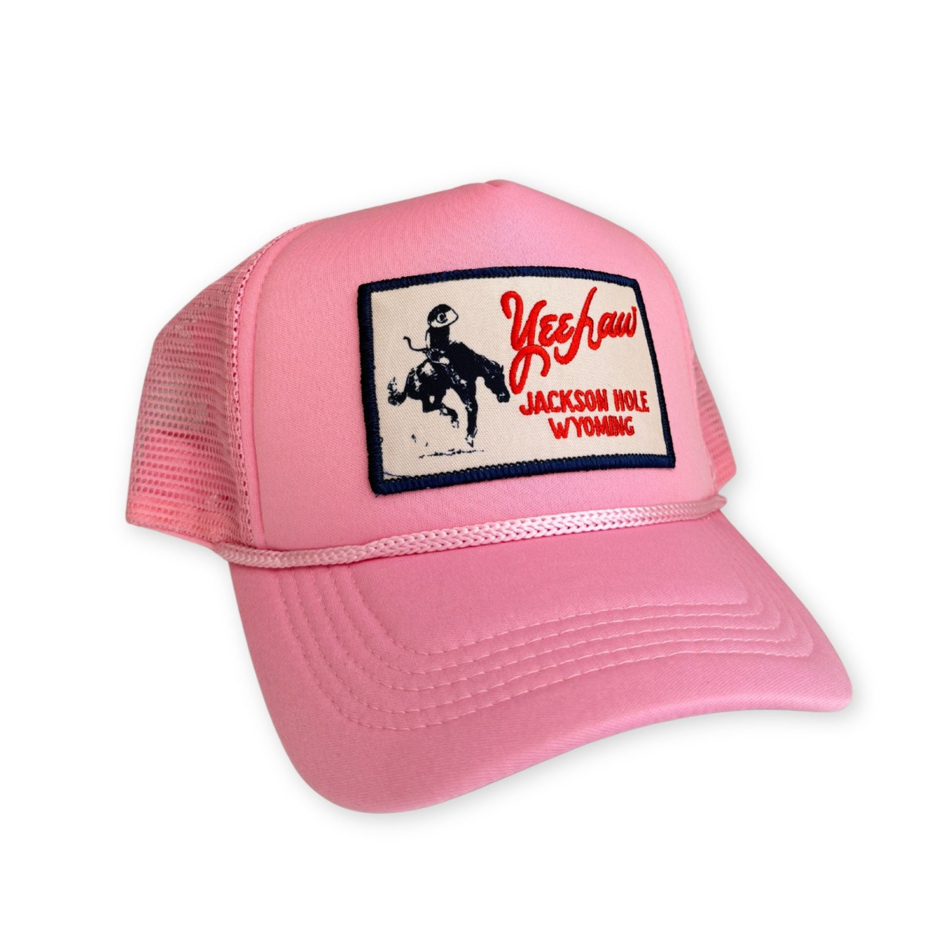Pink trucker hat with a patch on a white background that reads yeehaw