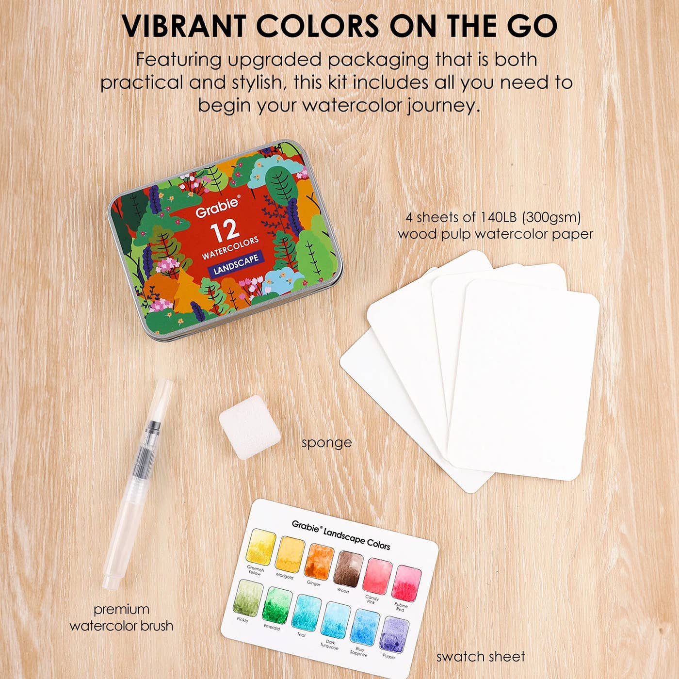 Grabcie watercolor set with tin, paper, brush, and swatch sheet on a wooden surface.